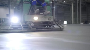 Endüstriyel ortam ve ortamda düz bir yüzey üzerinde ustalıkla çalışan beton bir bitiş makinesi. Kırp