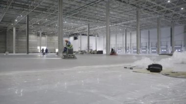 Büyük bir sanayi deposu yapım aşamasında ve çok sayıda işçi döşemeyi özenle tamamlıyor. Kırp