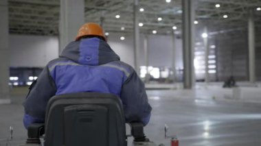 Modern verimliliği vurgulamak için büyük bir depoda makineyi ustalıkla kullanan bir endüstri işçisi. Kırp