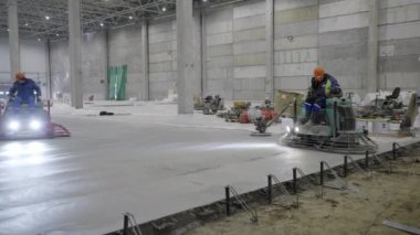 Yetenekli işçiler geniş, geniş bir sanayi bölgesindeki beton zemini titizlikle temizliyorlar. Kırp