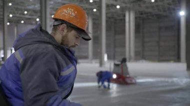 İşçiler, eğlence amaçlı buz pateni faaliyetleri için özel makineleri ve araçları olan bir buz pateni pisti hazırlıyorlar. Kırp