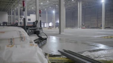 Bu geniş depo, yeni döşenmiş beton döşemeleri ve çeşitli inşaat ekipmanlarını cesurca sergiliyor. Kırp