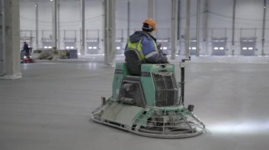 Yetenekli bir işçi geniş ve geniş bir sanayi bölgesinde betonu ustalıkla bitirmek için mala biniyor. Kırp