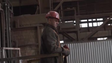 Sert bir şapka takan kendini işine adamış ve çalışkan bir işçi sanayi tesisindeki operasyonları izlemeye odaklanıyor. Menkul Kıymetler