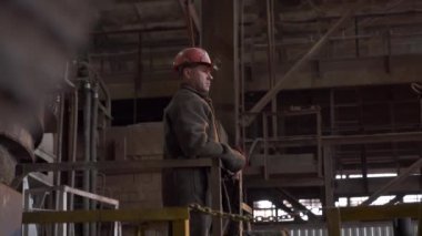 Endüstriyel bir ortamda, kendini işine adamış bir işçi koruyucu bir kask takıyor, tamamen odaklanmış ve tetikte. Menkul Kıymetler