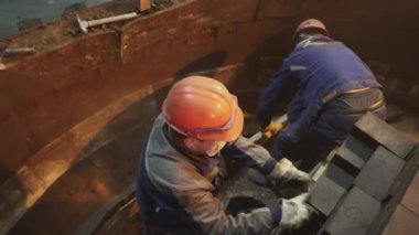 Kask ve eldiven takan iki yetenekli işçi, endüstriyel yapıyı dikkatlice onarıyor. Menkul Kıymetler