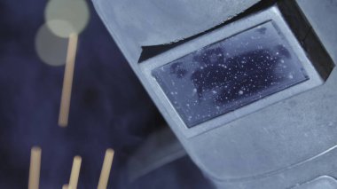 Arka planda belirgin bir şekilde parıldayan bir kaynak miğferinin detaylı bir yakın çekimi. Menkul Kıymetler