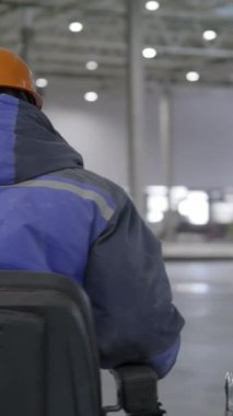 Modern verimliliği vurgulamak için büyük bir depoda makineyi ustalıkla kullanan bir endüstri işçisi. Kırp