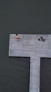 Sakin ve sakin sularla çevrili huzurlu bir ahşap iskelenin çarpıcı hava görüntüsü. Kırp