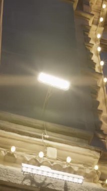 Büyük binaları aydınlatan güzel bir gece manzarası, karmaşık mimari detayları vurguluyor. Eylem