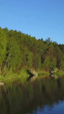 Sakin ve sakin bir nehir canlı yeşil yaprakları ve engebeli kayalık uçurumları yansıtarak mükemmel bir ahenk yaratır. Menkul Kıymetler