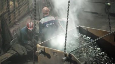Endüstriyel bir çevredeki işçiler, olağanüstü bir işçilik ve beceri sergileyerek erimiş metali ustalıkla idare ediyorlar. Menkul Kıymetler