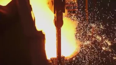 Dinamik bir sahnede, erimiş metal akar ve dökülür, metal işçiliğinde kıvılcımlar ve yoğun ısı ortaya çıkar. Menkul Kıymetler