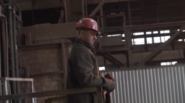 Sert bir şapka takan kendini işine adamış ve çalışkan bir işçi sanayi tesisindeki operasyonları izlemeye odaklanıyor. Menkul Kıymetler