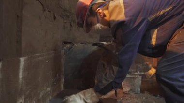 Çok yetenekli bir inşaat işçisi titizlikle endüstriyel ortamdaki bir duvara çimento sürüyor. Menkul Kıymetler