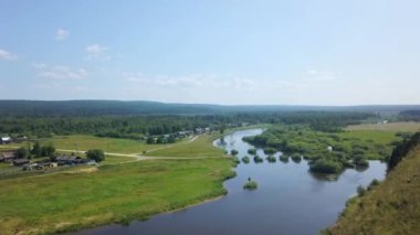Berrak mavi gökyüzünün altındaki yemyeşil çayırlarda zarafetle kıvrılan sakin bir nehrin şaşırtıcı derecede güzel bir manzarası. Kırp