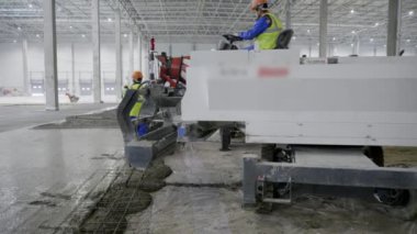 Yetenekli işçiler büyük bir depoda etkili beton yerleştirme için özel makineler kullanırlar. Kırp
