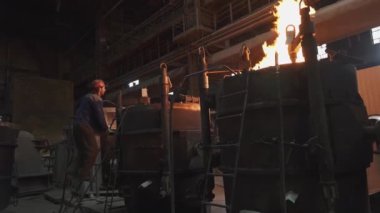 Fırınlardan çıkan yoğun alevlerle birlikte metal işleme süreçlerini gösteren endüstriyel bir sahne. Menkul Kıymetler