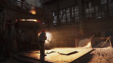 Fabrikaya erimiş metal döken bir sanayi işçisi, işçilik ve üretim süreçlerini sergiliyor. Menkul Kıymetler