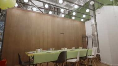 Uzun bir yemek masası, zevkli yeşil aksanlar ve şık, şık sandalyeler içeren çağdaş bir yemek odası tasarımı. Yaratıcı