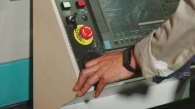 Bu resim, düğmeleri ve düğmeleri ayarlayan bir eli olan karmaşık bir kontrol panelinin yakın çekimini gösterir. Medya