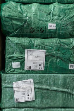 Parlak yeşil ambalajlı paketler, hareketli bir depo ortamında sevkiyat için dizildi ve hazırlandı.