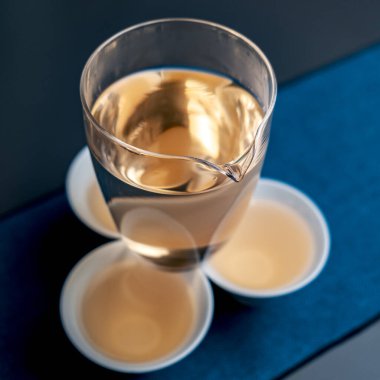 A beautifully designed glass full of aromatic tea, with delicate cups, set against a rich, dark backdrop clipart