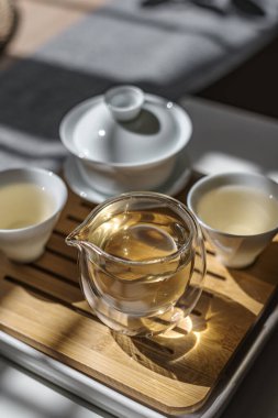 İçinde cam çaydanlık ve çay fincanı olan sakin bir çay seti bambu tepsisi, rahatlatıcı bir çay saati için mükemmel..