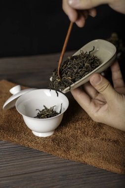Nazikçe yetenekli bir el gevşek, mis kokulu çay yapraklarını demleme işlemi için nefis bir seramik kaba döküyor.
