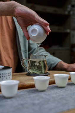 Nazik bir el, güzel işlenmiş cam bir fincana güzel kokulu çay döker. Huzurlu ve sıcak bir çay seremonisi anı yakalar.