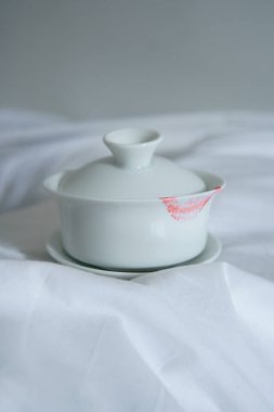 Zarif, beyaz bir porselen kapaklı, yumuşak kumaşa yerleştirilmiş, mutfak fotoğrafçılığı için mükemmel..