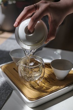 Huzurlu, huzurlu çay dökme sahnesi zarif bir şekilde sergileniyor. Minimalist çay fincanlarıyla birlikte güzel bir cam çaydanlık.