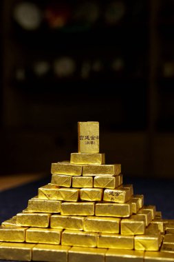 Altın külçe külçe külçelerinin şaşırtıcı bir düzenlemesi, lüks ve finansal başarıyı simgeleyen bir piramit oluşturuyor..