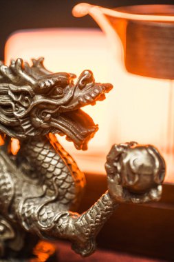 Güç ve bilgeliği temsil eden gümüş bir ejderha heykeli sıcak bir arkaplanda duruyor.