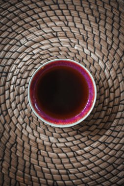 Karmaşık örülmüş bir paspasın üzerinde huzur içinde dinlenen enfes bir kahve fincanının inanılmaz sakinleştirici görüntüsü.