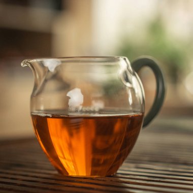 Ahşap bir yüzey üzerinde demlenmiş çayla dolu çarpıcı bir cam çaydanlık. Çay severler için mükemmel..