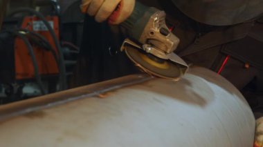 Metal işçiliğinin detaylı bir görüntüsü, atölyedeki metal bir boru üzerinde etkili bir açı öğütücü kullanımına odaklanıyor. Medya