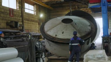 Endüstriyel atölye ortamında, işçiler çeşitli görevleri tamamlamak için ustalıkla ağır makineler kullanıyorlar. Medya