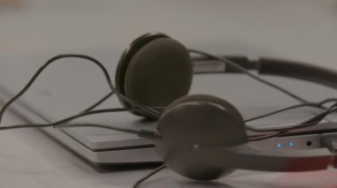 Şık bir kulaklık şık bir dizüstü bilgisayarın üzerinde rahatça dinleniyor ve çağdaş bir çalışma düzeneği sergiliyor. Stock Görüntüsü