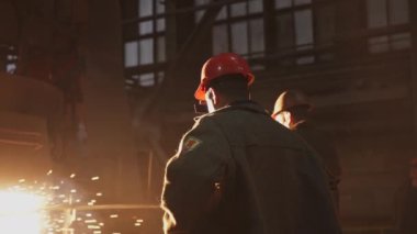 Kendini işine adamış iki fabrika işçisi canlı bir endüstriyel ortamda temel güvenlik protokollerini etkili bir şekilde sergiliyor. Menkul Kıymetler