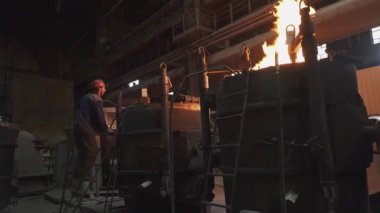 Fırınlardan çıkan yoğun alevlerle birlikte metal işleme süreçlerini gösteren endüstriyel bir sahne. Menkul Kıymetler