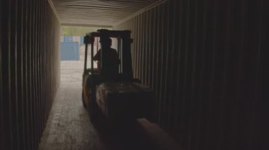 Bir forklift, endüstriyel lojistiğin karmaşıklığını gösteren yoğun bir konteyner koridorunda dikkatlice hareket ediyor. Stock Görüntüsü