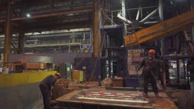 İşçiler, vinçler ve ağır ekipmanlarla çevrili yoğun bir sanayi ortamında çeşitli operasyonlarda bulundular. Menkul Kıymetler