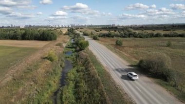 Nefes kesici bir hava çekimi, yol boyunca kıvrılan huzurlu bir nehri, yemyeşil tarlaları ve temiz bir gökyüzünü yakalar. Kırp