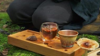 Rahatlatıcı bir videoda, sakin çay saatleri bir tepside sergilenir, doğada yudumlayan bir kişi, sakin sahneler, ve iki fincan arkadaşlığı davet eder. Medya