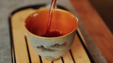 Huzurlu ve huzurlu bir an. El yapımı bir fincana çay doldurmanın rahatlatıcı hareketini güzel bir şekilde yakalıyor. Medya