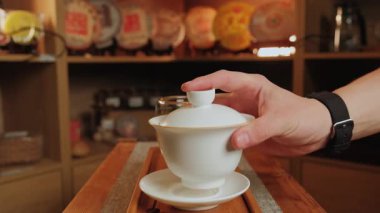 Bu video, ahşap bir masada, çay ve kahve doldurma, tefekkür etme anları ve samimi bir ortam içeren sakin bir içecek hazırlama ayinini vurguluyor. Medya