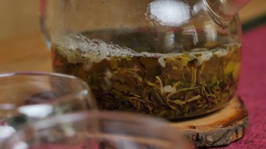 Video, cam çaydanlık ile serinletici yeşil çayı narin bir fincana dökerek rahatlatıcı bir atmosfer oluşturan sakin bir çay ayinini vurguluyor. Medya
