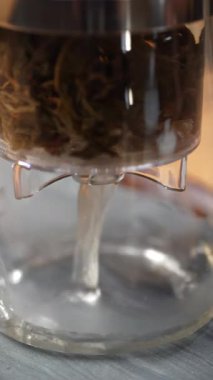 Kurumuş yapraklarla dolu, demleme sürecini vurgulayan bitkisel çay püskürtücüsünün yakın plan görüntüsü. Medya