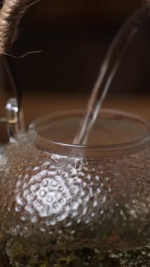 Dekoratif cam bir su ısıtıcısına dökülen su, görsel cazibe için karmaşık dokuları vurguluyor. Medya